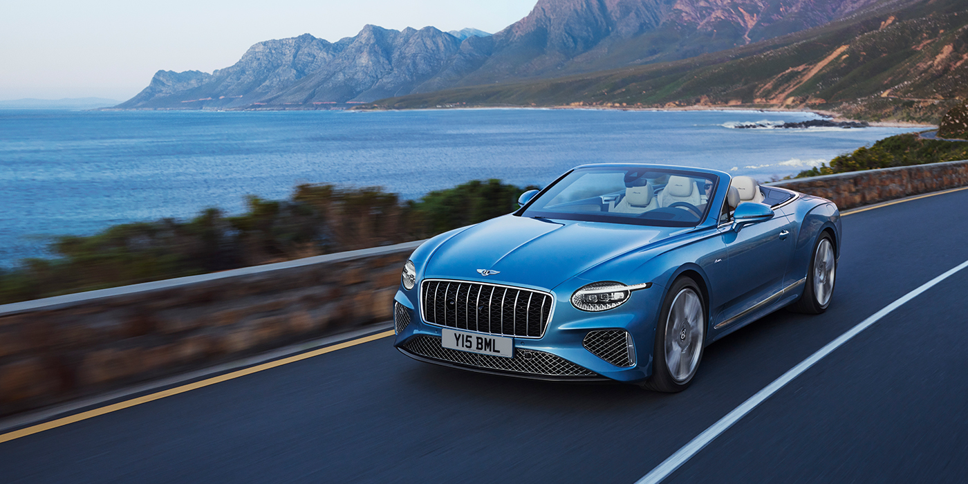 Bentley Brussels New Bentley Continental GTC Azure convertible in Light Windsor blue paint with 22 inch Azure wheels and chrome grill, driving dynamically by the sea