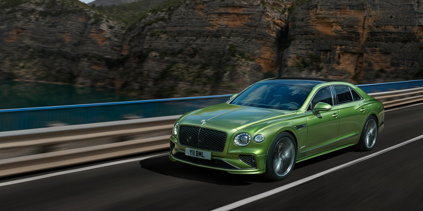 Bentley Brussels Bentley New Flying Spur Speed v8 hybrid sedan driving dynamically on a mountain road in Tourmaline Green paint