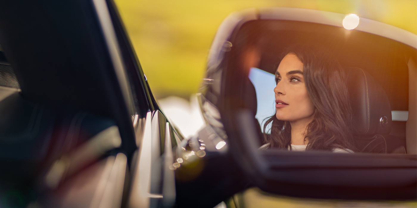 Bentley Brussels profile of dark haired woman's face in mirror of Bentley car in sunlight