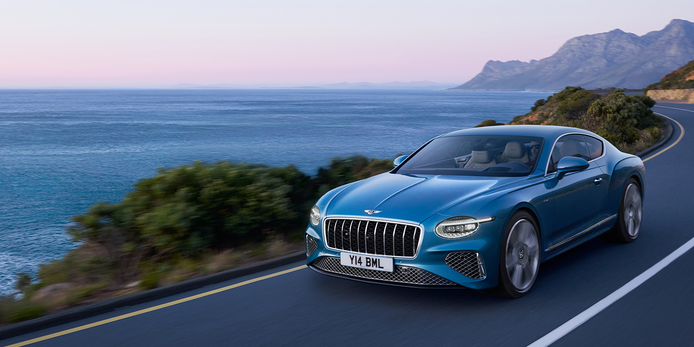 Bentley Brussels New Bentley Continental GT Azure coupe in Light Windsor blue paint with 22 inch Azure wheels and chrome grill, driving dynamically by the sea