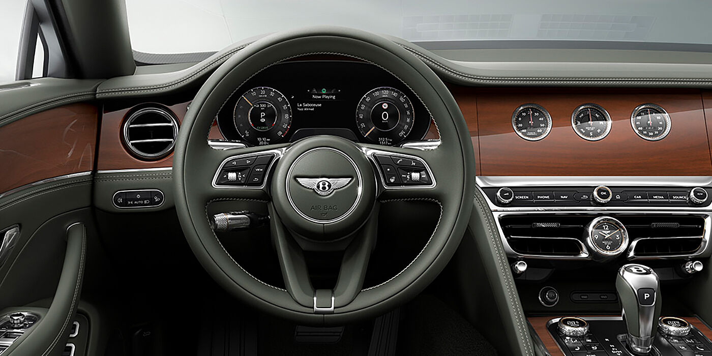Bentley Brussels New Bentley Flying Spur sedan front cabin in Cumbrian Green hide and Crown Cut walnut veneer showing steering wheel and Rotating Display with three clocks on face