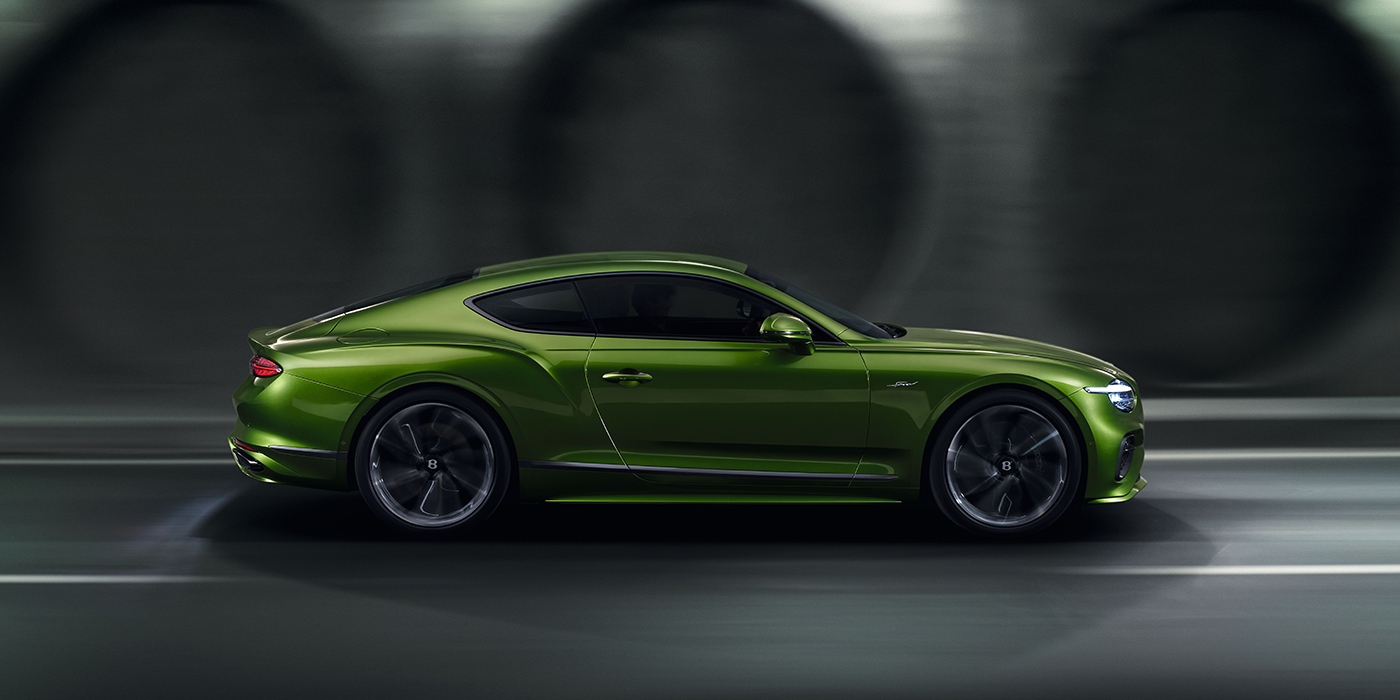 Bentley Brussels Bentley Continental GT coupe in Tourmaline Green paint driving in profile on a dark road