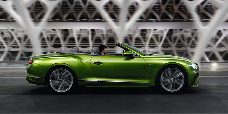 Bentley Brussels Bentley Continental GTC Speed convertible side profile in Tourmaline Green paint driving dynamically on a bridge at night