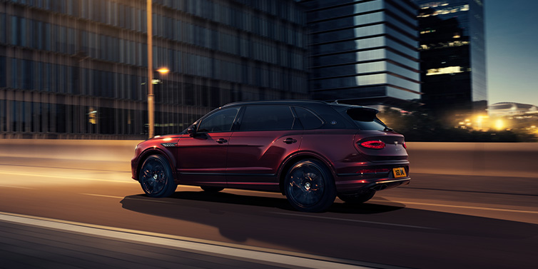 Bentley Brussels Bentley Bentayga Extended Wheelbase Mulliner SUV in Cricket Ball red paint driving dynamically in city at night