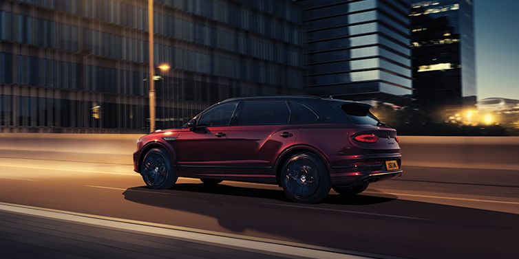 Bentley Brussels Bentley Bentayga Extended Wheelbase Mulliner SUV in Cricket Ball red paint driving dynamically in city at night