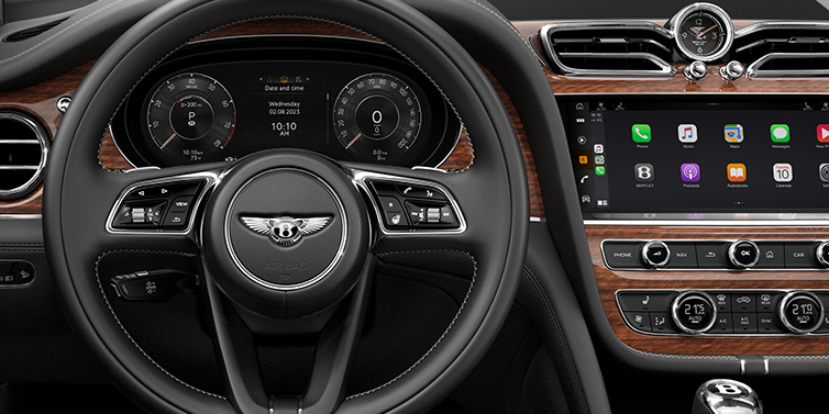 Bentley Brussels Bentley Bentayga SUV front interior detail of steering wheel and driver screens surrounded by Beluga black hide and Crown Cut Walnut veneer