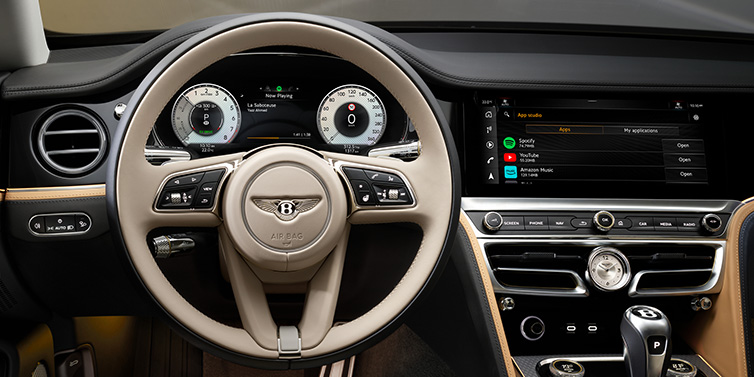 Bentley Brussels Bentley Flying Spur Mulliner sedan front interior detail of steering wheel and driver screens surrounded by Linen and Beluga black hides